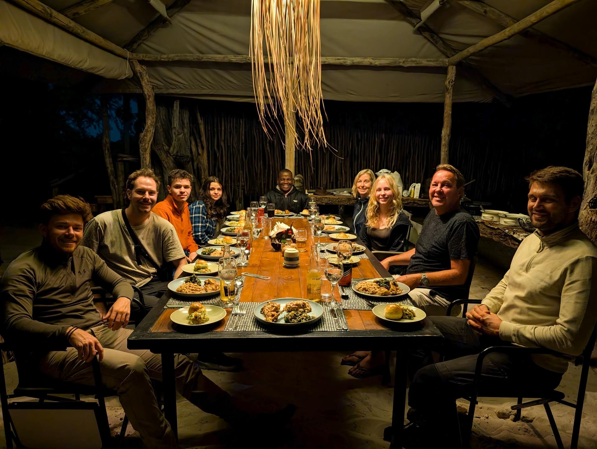 Guests at a shared dinner table in the Naledi Camp boma at night